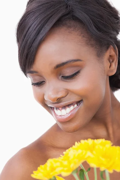 Frau lächelt und hält gelbe Blumen in der Hand — Stockfoto