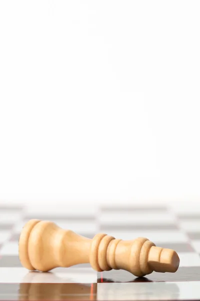 Белый шахматист лежит у шахматной доски — стоковое фото