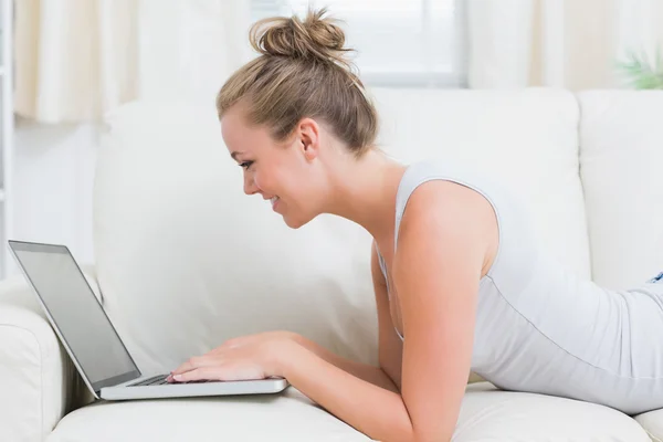 Mulher alegre usando laptop enquanto está deitado — Fotografia de Stock