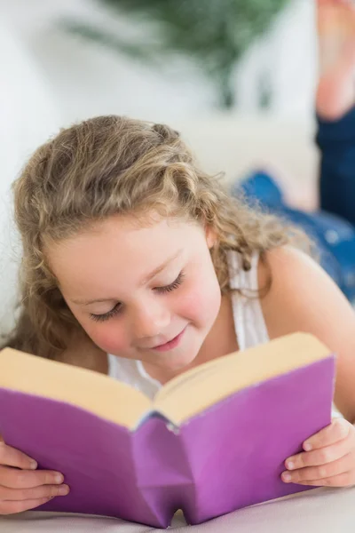 Mädchen liegt mit Buch auf dem Sofa — Stockfoto