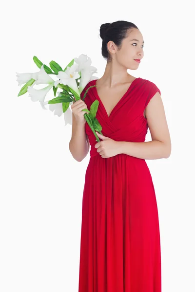 Mulher de vestido vermelho segurando lírios — Fotografia de Stock