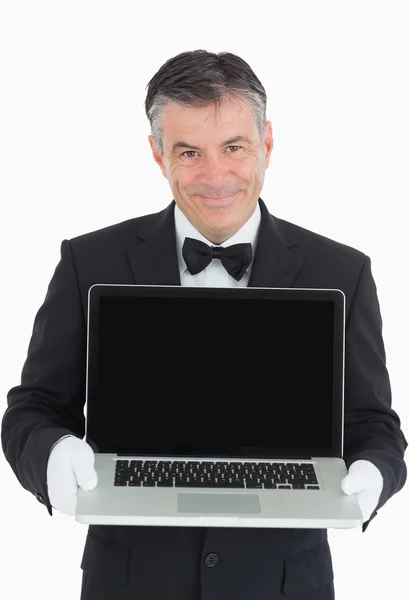 Улыбающийся официант показывает нам что-то на ноутбуке — стоковое фото