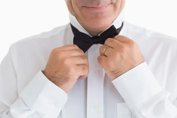 Smiling man fixing bow tie — Stock Photo, Image