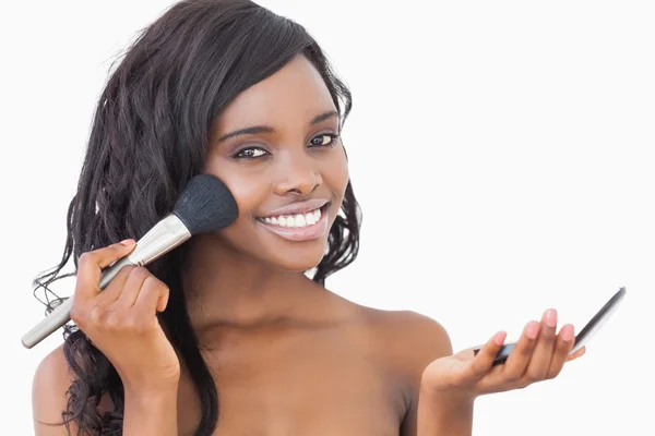 Woman holding powder and a brush to her face — Stock Photo, Image