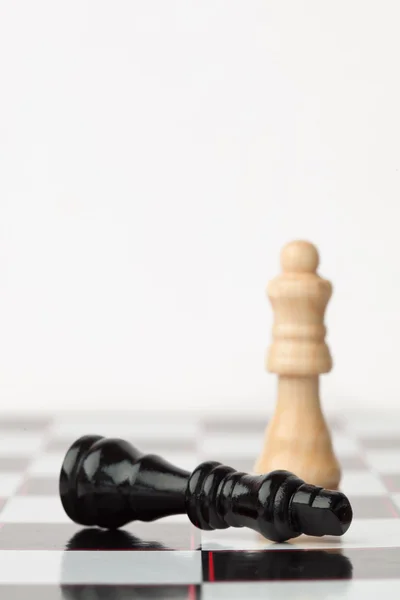 Black chess piece lying while white standing — Stock Photo, Image