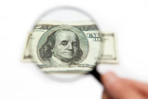 Hand holding magnifying glass over dollar bill — Stock Photo, Image
