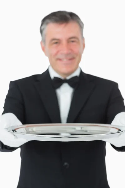 Waiter looking at the camera while holding a silver tray — Stock Photo, Image