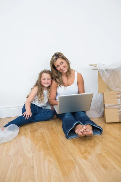 Smiling daughter and mother sitting on the floor — Stock Photo, Image