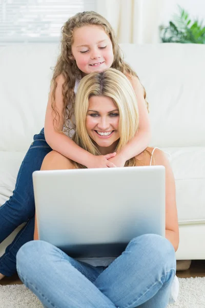 Mother using notebook while sitting on the floor — Stok fotoğraf