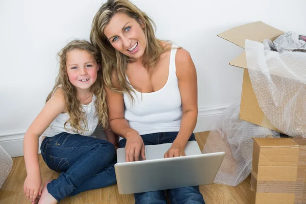 Mãe e filha sentadas no chão e usando laptop — Fotografia de Stock