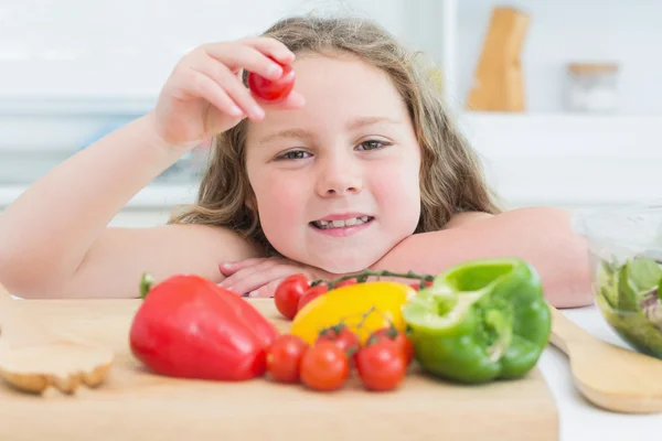 Little girl holding up cherry tomato — Stock Photo, Image