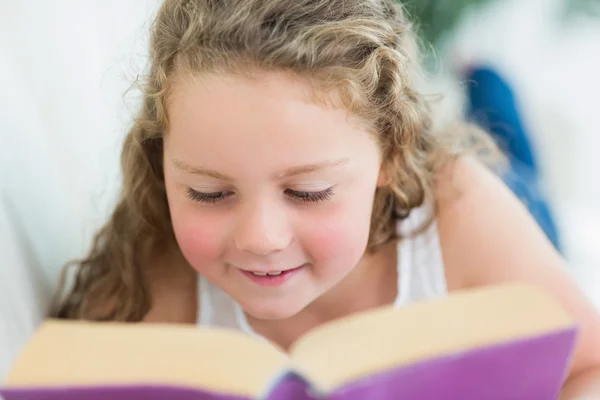 Mädchen liest ein Buch auf dem Sofa — Stockfoto