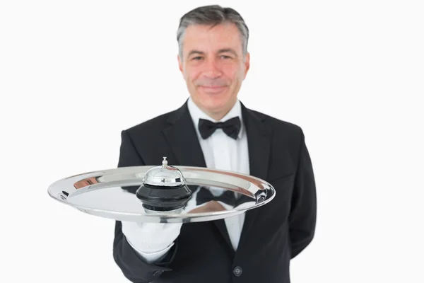 Smiling man holding a hotel bell on a tray — Stock Photo, Image