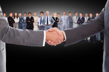Businessmen shaking hands with large team behind them clipart