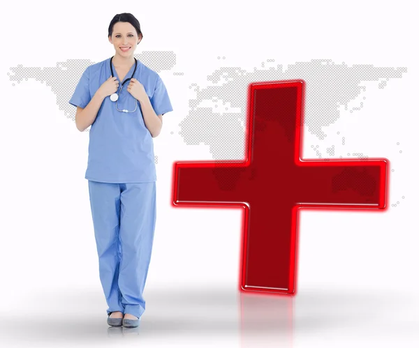 Nurse standing by digital red cross — Stock Photo, Image