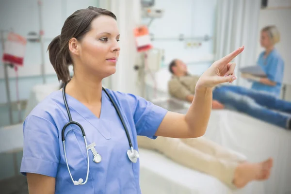 Nurse in hospital ward pointing to something — Stock Photo, Image