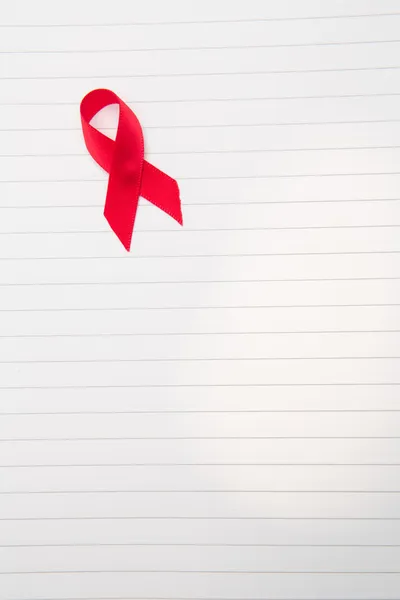 Awareness ribbon for aids on lined paper — Stock Photo, Image