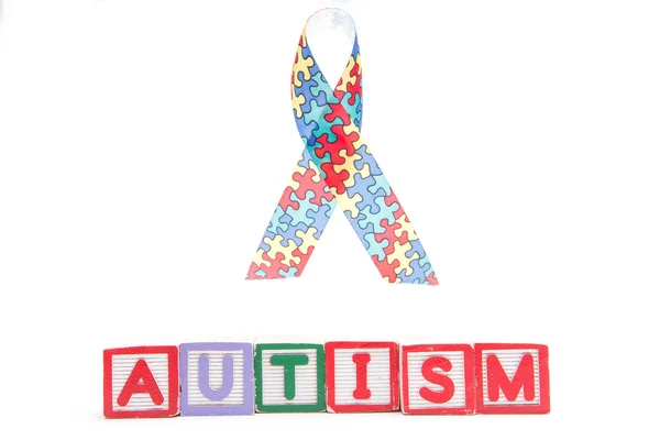Autismus povědomí stuhu vedle skládaný bloky pravopisu autismu — Stock fotografie