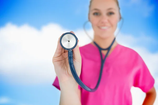 Glückliche Krankenschwester hält Stethoskop hoch — Stockfoto