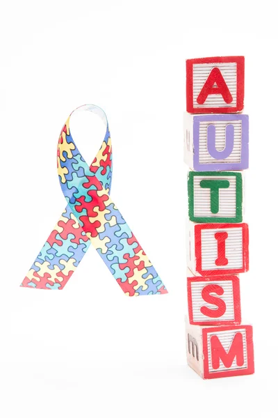 Autism awareness ribbon beside stacked blocks spelling autism — Stock Photo, Image