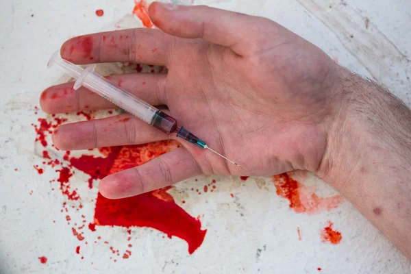 Leblose Hand mit blutiger Spritze — Stockfoto