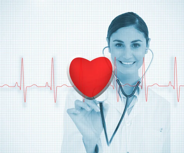 Doctor holding stethoscope up to red ECG line with heart graphic — Stock Photo, Image