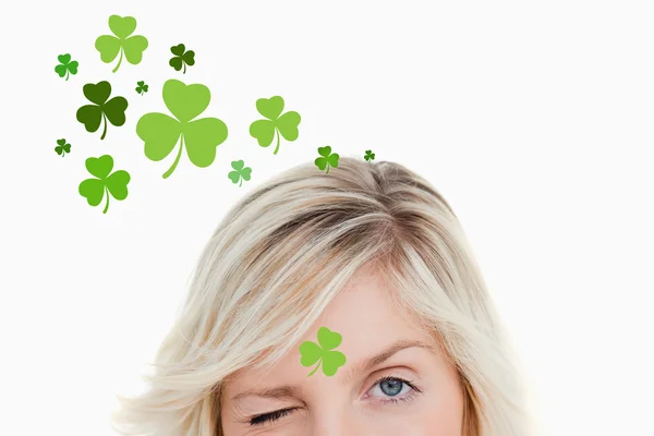 Blonde vrouw knipogend op shamrock achtergrond — Stockfoto