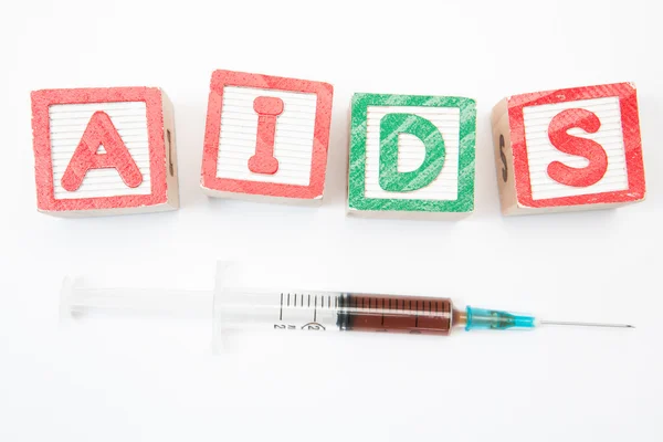 Wood blocks in green and red spelling out aids with syringe — Stock Photo, Image