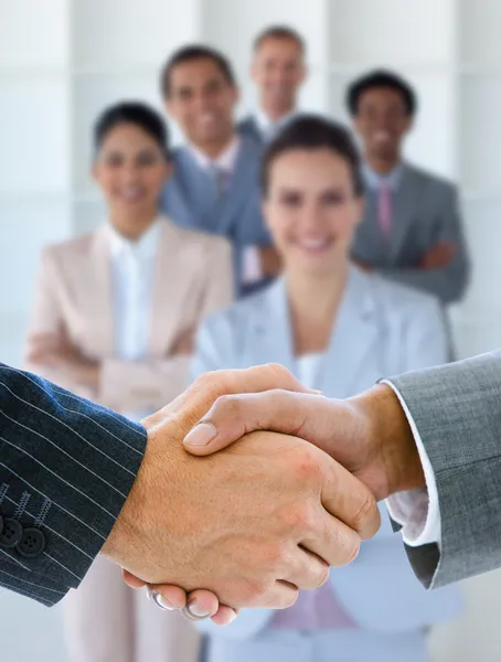 Businessmen shaking hands with team behind them — Stock Photo, Image