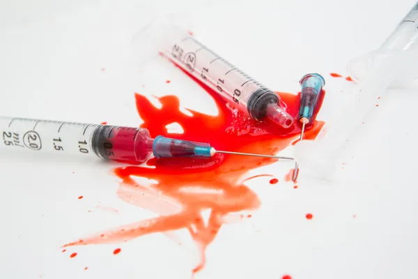 Three broken needles in pool of blood — Stockfoto