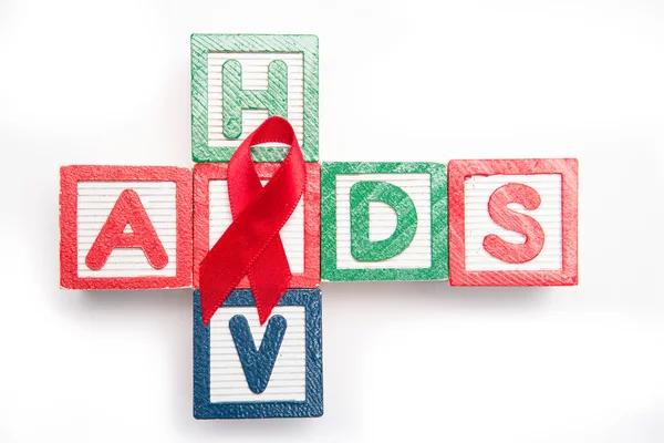 Fa blokkok helyesírás aids és hiv egy kereszt alakú piros tudatosság szalaggal — Stock Fotó