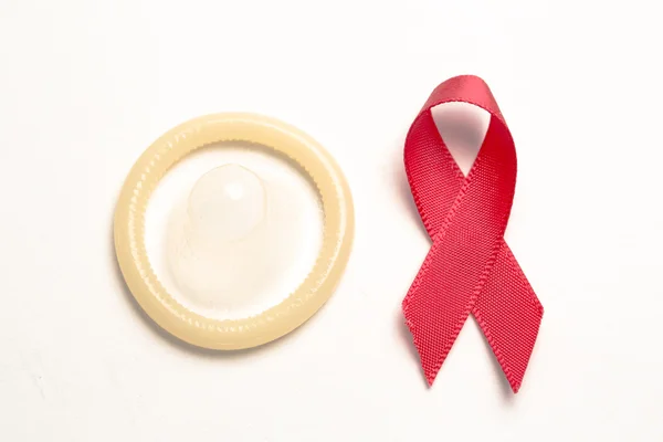 Condom peeking out from pocket with red awareness ribbon — Stock Photo, Image