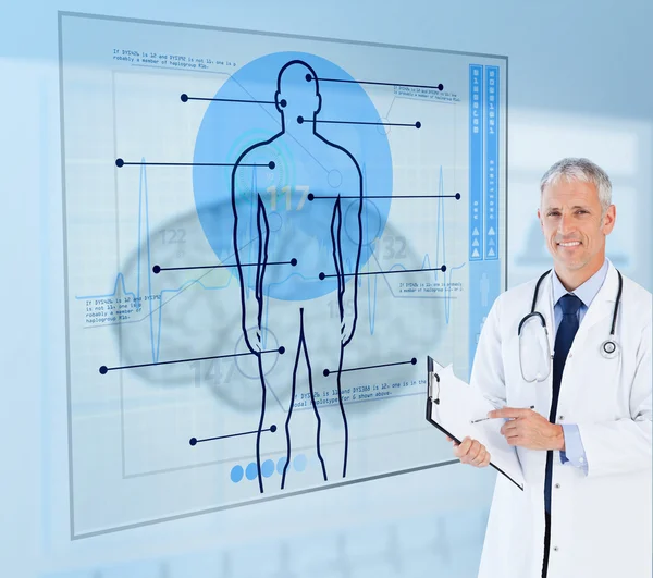 Senior doctor holding a clipboard beside display screens — Stock Photo, Image