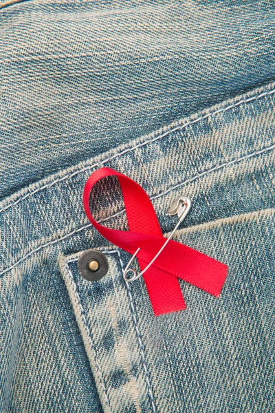 Aids awareness ribbon pinned to jeans — Stock Photo, Image