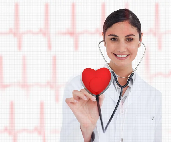 Médico segurando estetoscópio até gráfico coração vermelho — Fotografia de Stock