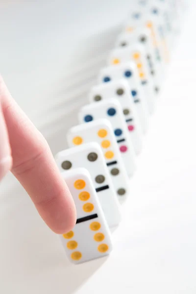 Finger på att slå över rad dominobrickor — Stockfoto