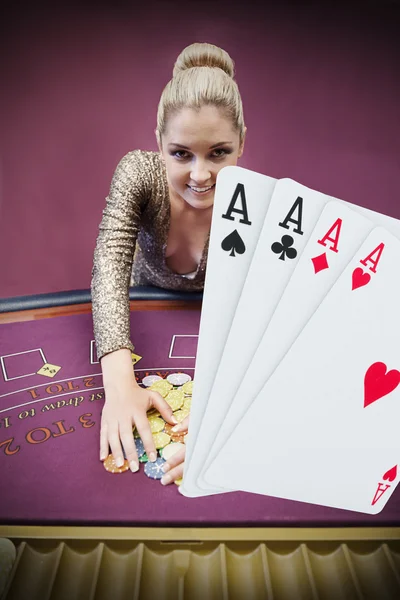 Blonde woman grabbing chips with digital hand of four aces — Stock Photo, Image