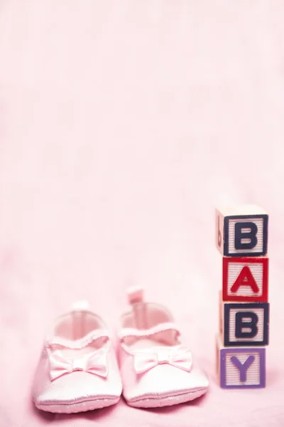 Baby Mädchen rosa Booties neben Blöcken, die Baby buchstabieren — Stockfoto