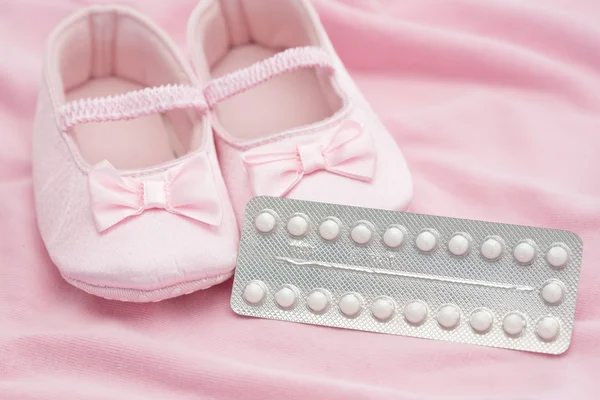 Anticonceptiepil pakket met baby slofjes — Stockfoto