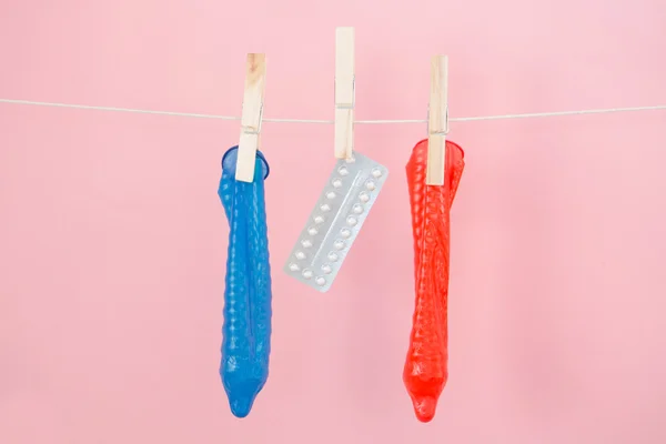 Contraceptive pill and condoms hanging from line — Stock Photo, Image