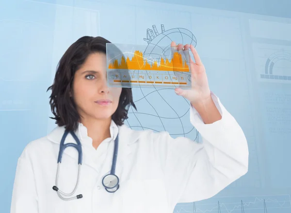 Brünette Ärztin schaut sich eine Grafik mit futuristischer Technologie an — Stockfoto