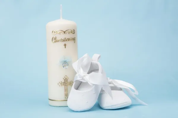 Хрестильна свічка для хлопчика з білими дитячими пінетками — стокове фото