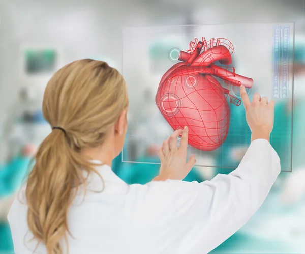 Blonde doctor consulting heart diagram on touchscreen display — Stock Photo, Image