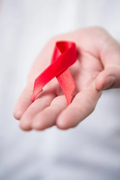 Man holding out red aids awareness ribbon — Stock Photo, Image