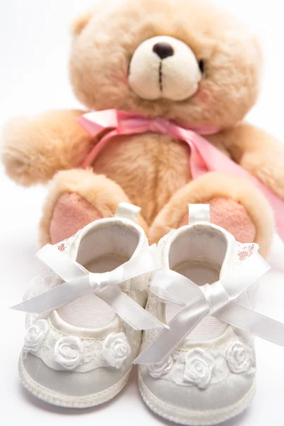 Teddy bear voor een meisje met witte baby slofjes — Stockfoto