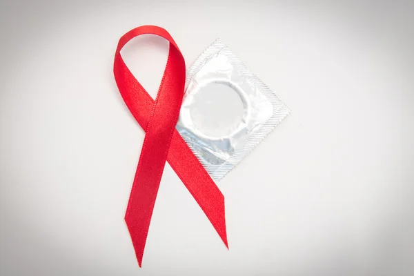 Red Aids ribbon beside condom — Stock Photo, Image