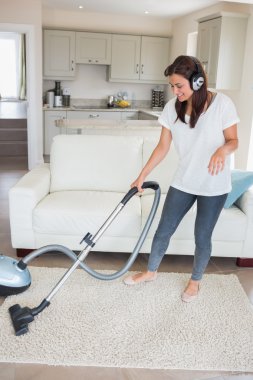 Woman wearing headphones while hoovering clipart
