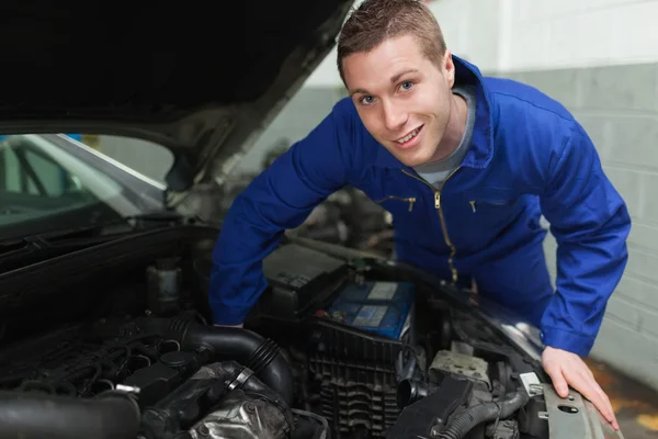 Happy mechanic repairing under car hood — Stock Photo, Image