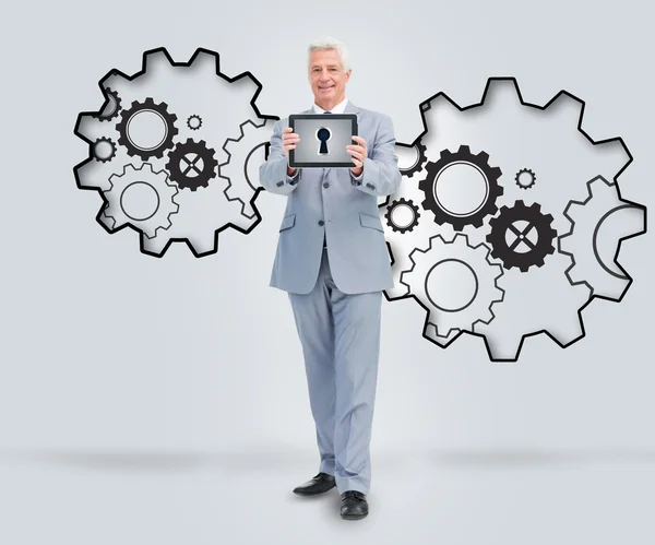 Smiling businessman holding a tablet against a background — Stock Photo, Image