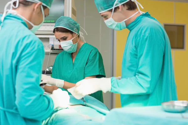 Cirurgiões trabalhando em um paciente com suas equipes — Fotografia de Stock